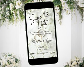 Può includere: Un annuncio digitale di salvataggio della data sullo schermo di uno smartphone. L'annuncio è per il matrimonio di Maddie & Tyler sabato 18 giugno 2026. Lo sfondo è un design floreale bianco e verde con due anelli dorati.
