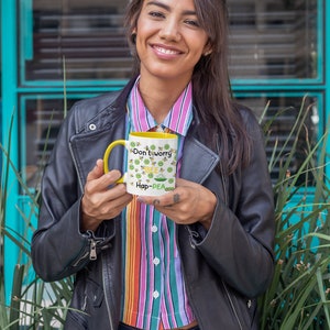 Può includere: Una tazza in ceramica gialla e bianca con un design a piselli verdi e il testo "Don't worry bee hap-pea".