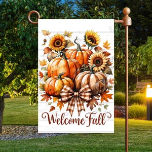 Könnte beinhalten: Eine Gartenflagge mit einem Aquarelldesign mit Kürbissen, Sonnenblumen und Herbstblättern. Die Flagge hat einen weißen Hintergrund mit den Worten "Welcome Fall". Unten befindet sich eine braun-weiß karierte Schleife.