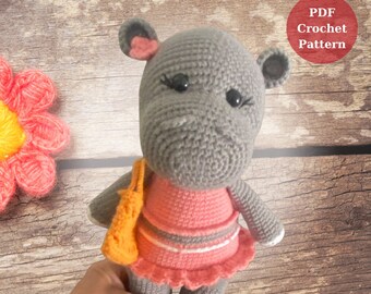 May include: A gray crocheted hippopotamus wearing a pink dress with white stripes and a yellow crocheted bag.  PDF Crochet Pattern.