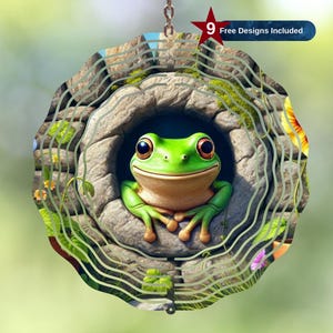 Può includere: Un ornamento da giardino circolare con una rana verde che spunta da una struttura simile a una pietra. L'ornamento ha un design a strati con accenti floreali e di fogliame. Il testo "9 Free Designs Included" è visibile. Appeso a una catena.