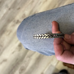 May include: A silver bracelet with a braided design.