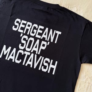 May include: Black t-shirt with white text that reads "Sergeant 'Soap' MacTavish"
