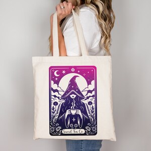 Tarot card design graphic with a mysterious woman wearing a hooded cloak and drinking tea, surrounded by wildflowers, stars and large moon in the sky. Text Suriel Tea Co at the bottom. ACOTAR inspired PNG SVG DXT cut file. Perfect for print on demand