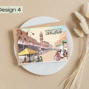 K&ouml;nnte beinhalten: Aquarell-Gru&szlig;karte mit einer Stra&szlig;enszene, Moschee und Marktst&auml;nden. Der Text "Design 4" und arabische Schrift sind zu sehen. Die Karte liegt auf einem wei&szlig;en Teller, begleitet von getrockneten Blumen.