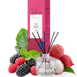 May include: Aromatic diffuser with the text "Red Berries" and the brand name "Sabrise". The product is in a clear glass bottle with black reeds, surrounded by fresh red berries, blackberries, and green leaves. A pink box is in the background.