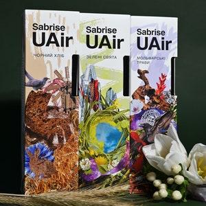 May include: Three boxes of air freshener with different scents. The boxes are white with black text and colorful images. The scents are "Black Bread", "Green Herbs", and "Molfar Herbs".