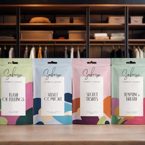 Può includere: Quattro sacchetti aromatici colorati del marchio "Gabrise" con vari nomi di profumi. I sacchetti sono in tonalità di verde, blu, rosa e verde, con disegni astratti e testo. Lo sfondo mostra un armadio di legno.