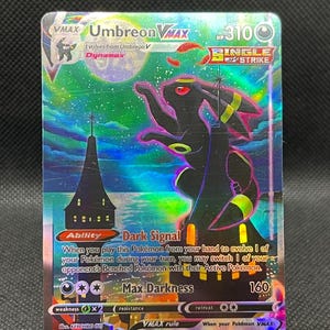 May include: A holographic Umbreon VMAX Pokémon card. The card features a black Umbreon with yellow accents, set against a night sky with a castle silhouette. The card text includes "Umbreon VMAX", "Dark Signal", and "Max Darkness".