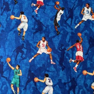 Könnte beinhalten: Ein blauer Stoff mit einem sich wiederholenden Muster aus Basketballspielern in verschiedenen Aktionsposen, darunter Springen, Dribbeln und Werfen. Die Spieler tragen weiße, rote oder grüne Trikots mit Nummern, und orangefarbene Basketbälle sind verteilt.
