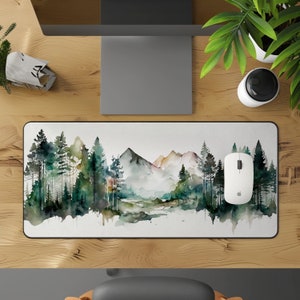 Op de afbeelding: Een muismat in aquarelstijl met een landschapsscène met bergen, bomen en een rivier. De muismat is wit met een zwarte rand en heeft een subtiel aquareleffect.