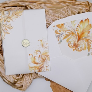 Puede incluir: Juego de tarjeta de invitación y sobre blancos con diseño floral dorado y naranja. La invitación tiene un sello de lámina dorada con la palabra "Love". El interior del sobre presenta un patrón floral a juego.