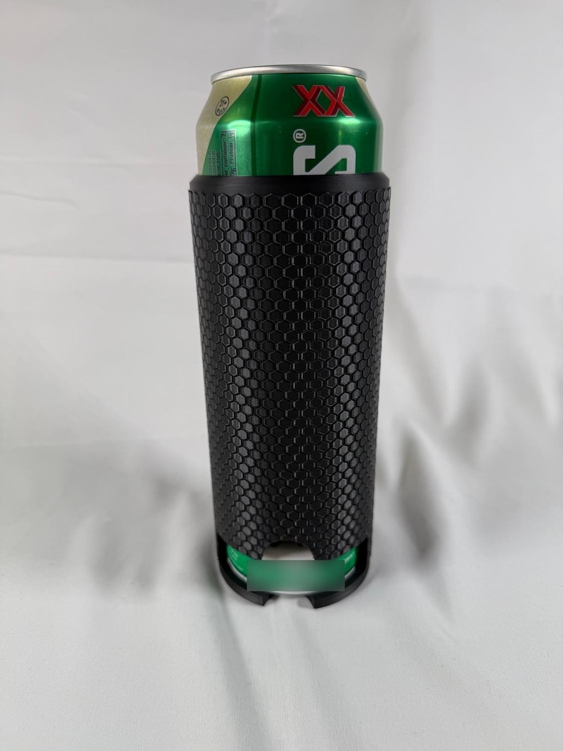 May include: A black, textured can cooler with a honeycomb pattern, holding a green and gold can. The cooler has a cylindrical shape and a green base, designed to keep beverages cold.