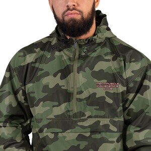 Könnte beinhalten: Eine grüne Tarnjacke mit Kapuze, Reißverschluss und dem gestickten Schriftzug "Mentmuscle Calisthenics Club" auf der Vorderseite.