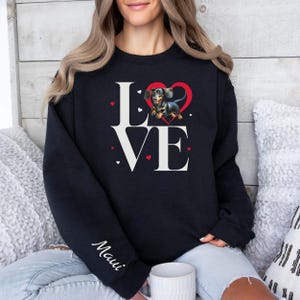 May include: Black sweatshirt with a white "LOVE" graphic featuring a dachshund inside a red heart. The text "Maui" is on the left sleeve.