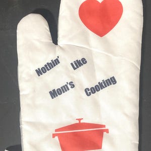 May include: White oven mitt with a red heart, a red pot, and the text "Nothin' Like Mom's Cooking" in blue.