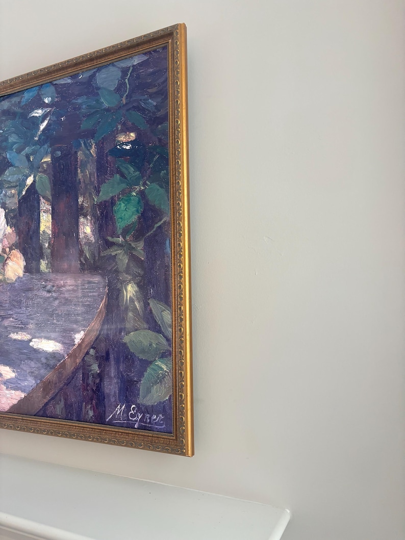 May include: A framed painting with a gold-colored ornate frame. The artwork depicts a landscape scene with trees, foliage, and a table. The painting is signed "M. Eyner" in the lower right corner. The color palette includes shades of blue, green, and purple.