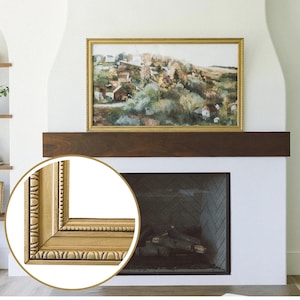 May include: A gold picture frame with a detailed ornate design. The frame is hanging above a fireplace with a wood mantel.