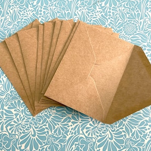 May include: A stack of brown kraft paper envelopes, folded and ready to be used for mailing letters or small items.
