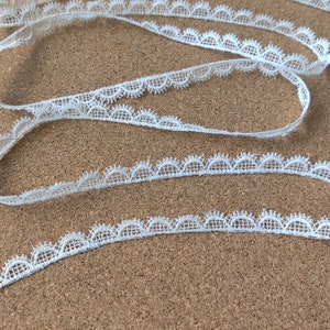 May include: White lace trim with a scalloped edge. The trim is delicate and has a soft, feminine look.