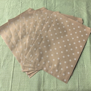 May include: A stack of brown paper bags with white polka dots. The bags are folded and stacked on top of each other.