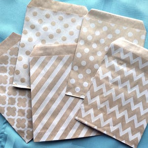 May include: Five brown paper gift bags with different white patterns. The patterns include polka dots, stripes, zigzags, and a geometric design.