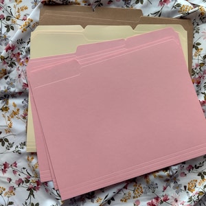 May include: A stack of pink, beige, and brown file folders. The folders are made of sturdy cardstock and have a smooth finish.