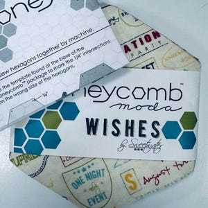 May include: Honeycomb Moda fabric package with the word "Wishes" and a geometric design in teal, green, and white. The package includes instructions and a fabric piece with travel-themed stamps.