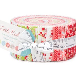 May include: A rolled bundle of fabric strips in various shades of red, pink, and green, tied with a white ribbon printed with a ruler and the word "moda". The label reads "Little Ruby" by Bonnie & Camille.