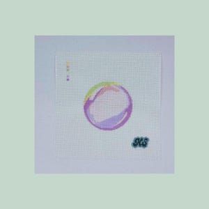 May include: A needlepoint canvas featuring a colorful bubble design. The bubble has shades of pink, purple, yellow, and green. A small color palette is on the left, and the initials "JCS" are in the bottom right corner.