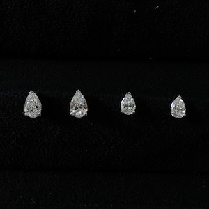 May include: Four pear-shaped diamond stud earrings of varying sizes are displayed against a black background. The diamonds sparkle, showcasing their facets. The earrings are arranged in a row, highlighting their graduated sizes.