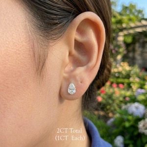 May include: A white ceramic mug with a black handle and the text "But First, Coffee" in a handwritten style. The mug is on a white surface. The mug is approximately 4 inches tall.