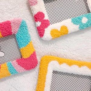 May include: Four colorful yarn photo frames with different designs. The frames are made with a variety of colors, including pink, yellow, blue, and white. The frames are all 4x6 inches and are perfect for displaying photos or artwork.