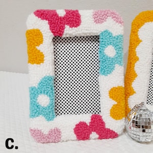 Colorful handmade punch needle photo frames in bright pink, yellow, blue, and white yarn. These 4x6 hand-tufted picture frames are perfect for fun, playful decor. Cozy textured frame designs ideal for desk styling, room decor, or unique gifts.