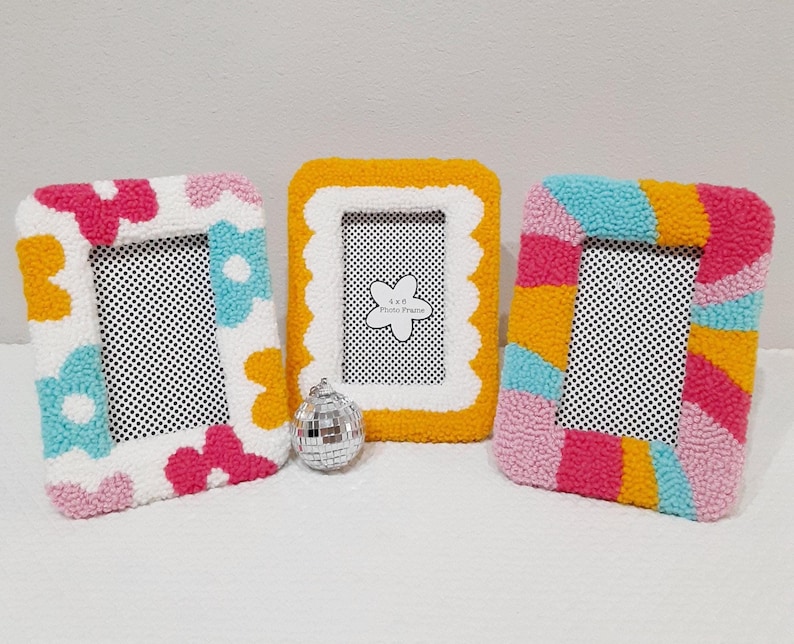 Colorful handmade punch needle photo frames in bright pink, yellow, blue, and white yarn. These 4x6 hand-tufted picture frames are perfect for fun, playful decor. Cozy textured frame designs ideal for desk styling, room decor, or unique gifts.