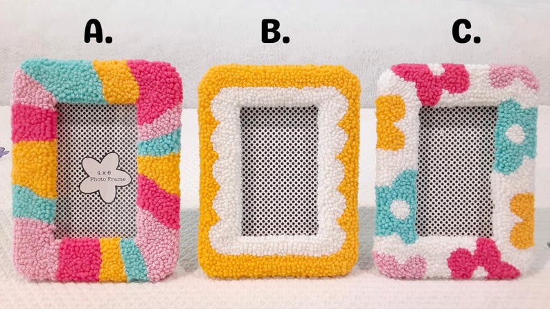May include: Three colorful, handmade photo frames with different designs. The first frame has a striped design in pink, yellow, and blue. The second frame has a white scalloped border with a yellow background. The third frame has a white background with pink, yellow, and blue flowers.