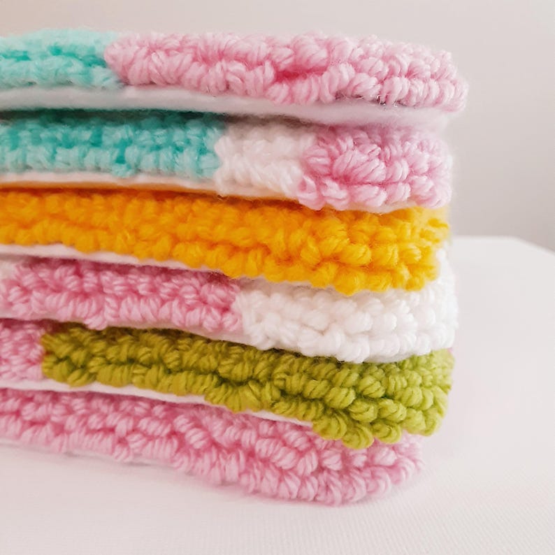 May include: A stack of six colorful, round, hand-stitched felt pieces. The pieces are layered in a rainbow pattern, with pink, turquoise, yellow, pink, white, and green.