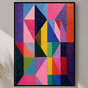 Puede incluir: Impresión artística geométrica abstracta en un marco negro. La obra presenta una colorida disposición de triángulos y rectángulos en tonos rosa, azul, amarillo, verde y naranja. La superficie texturizada añade profundidad al diseño moderno.