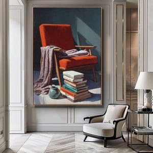 May include: A framed painting depicts a mid-century modern style chair in a room. The chair is upholstered in a vibrant orange fabric, with a patterned blanket draped over it. A stack of books and a small vase are in front of the chair.
