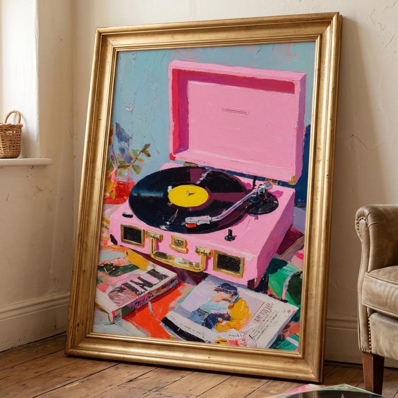 May include: An oil painting in a gold frame depicting a bright pink portable record player with a black vinyl record on the platter. The turntable sits atop a surface scattered with magazines and books, rendered with visible brushstrokes and vibrant colours.