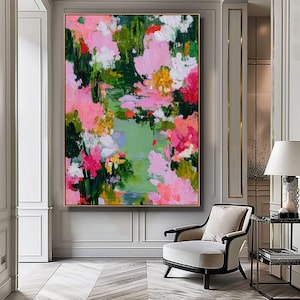 May include: Large abstract painting with a gold frame. The artwork features a vibrant mix of colors, including pink, green, white, and yellow, creating a floral or landscape-inspired composition. The brushstrokes are visible, adding texture to the piece.