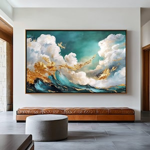 May include: Large framed abstract painting depicting a dynamic ocean scene. The artwork features a teal and gold wave crashing beneath fluffy white clouds against a teal and turquoise sky. The painting is displayed above a brown leather bench.