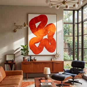May include: A living room scene featuring a large abstract painting with orange brushstrokes on a white background. The room includes a mid-century modern wooden cabinet, a leather sofa, and a black leather armchair with an ottoman. A record player sits on a small wooden stand.