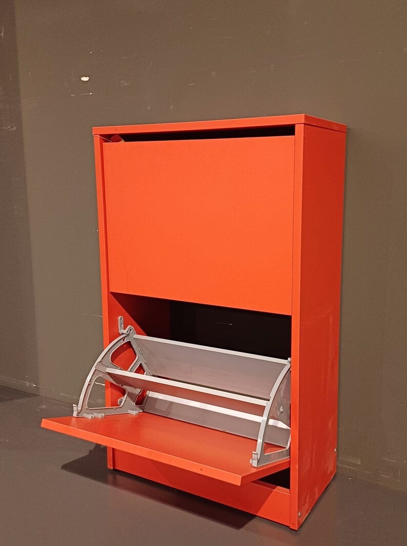 May include: A red shoe storage cabinet with a flip-down door and a pull-out shelf. The shelf is made of metal and has a silver finish.