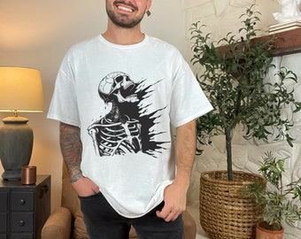 May include: A white short-sleeved t-shirt featuring a black graphic print of a skeleton torso with its head tilted back and mouth open, surrounded by abstract black ink-like splashes and drips on the chest area of the garment.