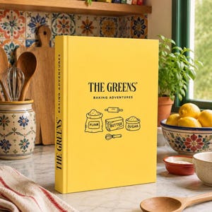 May include: A bright yellow hardback book titled The Greens' Baking Adventures with black text and line art illustrations of a flour sack, a butter block, sugar, a rolling pin, and a whisk on the front cover and spine.