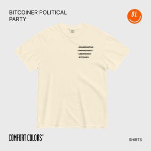 Könnte beinhalten: Cremefarbenes T-Shirt mit dem Text "BITCOINER POLITICAL PARTY" oben und "COMFORT COLORS" unten. Das Shirt zeigt eine Liste politischer Zugehörigkeiten: "CONSERVATIVE, PROGRESSIVE, LIBERTARIAN, BITCOINER" in schwarzem Text.