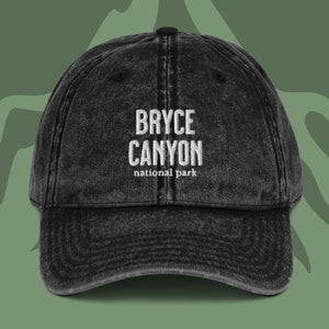 May include: Black distressed denim baseball cap with white embroidered text that reads "BRYCE CANYON national park".