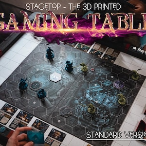 Könnte beinhalten: Ein 3D-gedruckter Spieltisch mit einem schwarz-weißen Gittermuster und einem blau-grauen Spielbrett. Der Tisch hat eine weiße Oberfläche und schwarze Kanten. Der Text "Stagetop - The 3D Printed Gaming Table" wird in einer feurigen Schriftart über dem Tisch angezeigt. Der Text "Standard Versions" wird in Weiß auf schwarzem Hintergrund am unteren Rand des Tisches angezeigt.