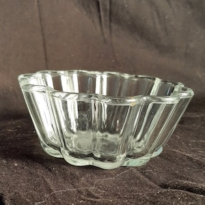 Op de afbeelding: Een glazen kom met een geribbeld ontwerp. De kom heeft een gegolfde rand en is perfect voor het serveren van desserts of salades.